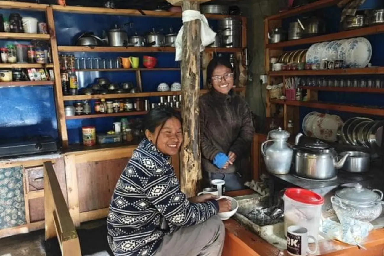 Local residents smiling inside a traditional mountain kitchen featured in the Annapurna Circuit Trek Guide.
